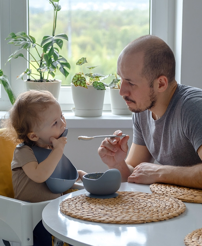 Single parent supporting his child by giving him food with a spoon